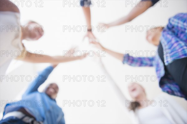 Close up of teenagers cheering with arms outstretched in huddle