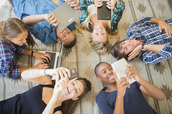 Teenagers laying on floor using technology