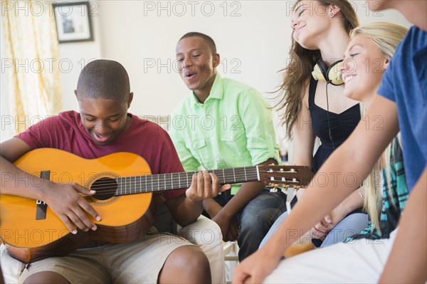 Teenage boy playing guitar at party