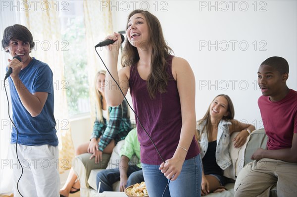 Teenagers singing karaoke at party