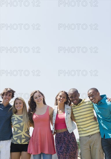 Smiling teenagers hugging under blue sky