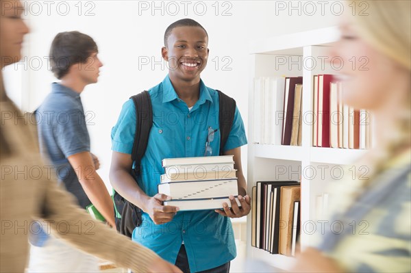 Teenage boy carrying books in library