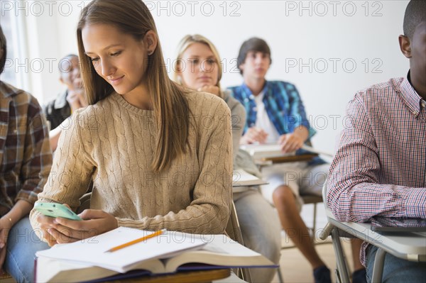 Teenage student using cell phone in classroom