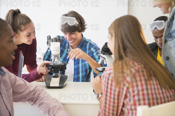 Teenage students using microscope in science laboratory
