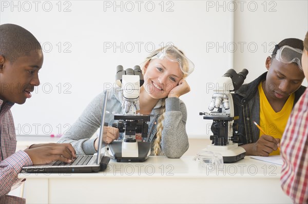 Teenage students using microscopes in science laboratory