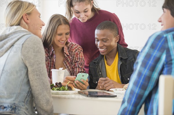 Teenagers using cell phone at table