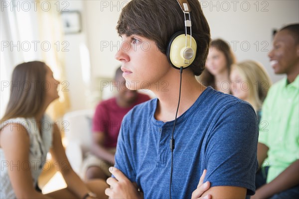 Teenage boy listening to headphones at party