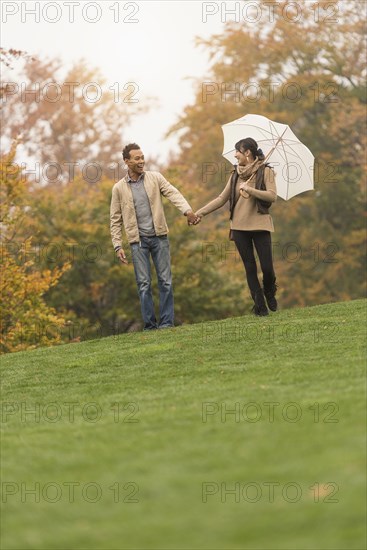 Couple walking with umbrella in park