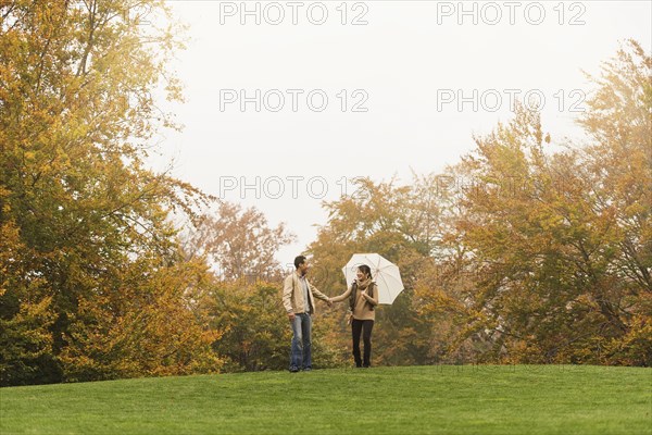 Couple walking with umbrella in park