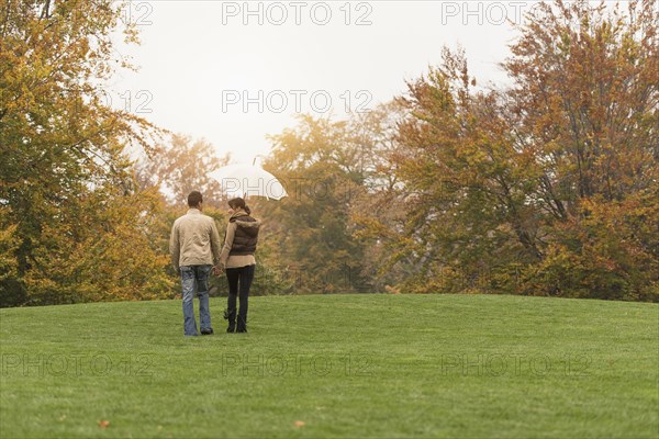 Couple walking with umbrella in park