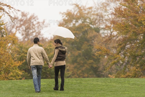 Couple walking with umbrella in park