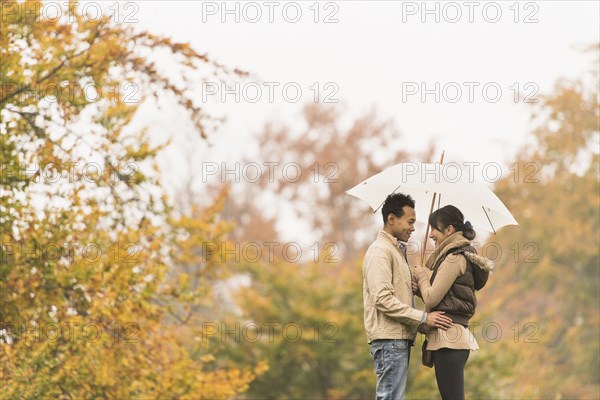 Couple standing with umbrella in park