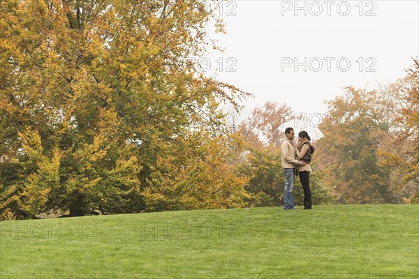 Couple standing with umbrella in park