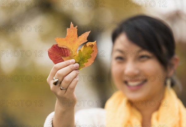 Asian woman admiring autumn leaves outdoors