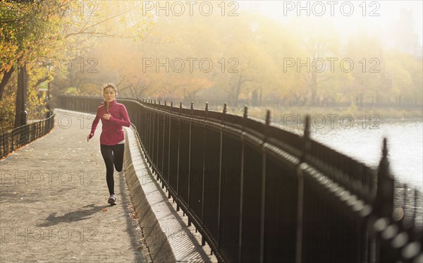 Asian woman running on waterfront path