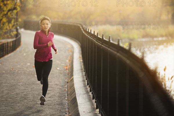 Asian woman running on waterfront path