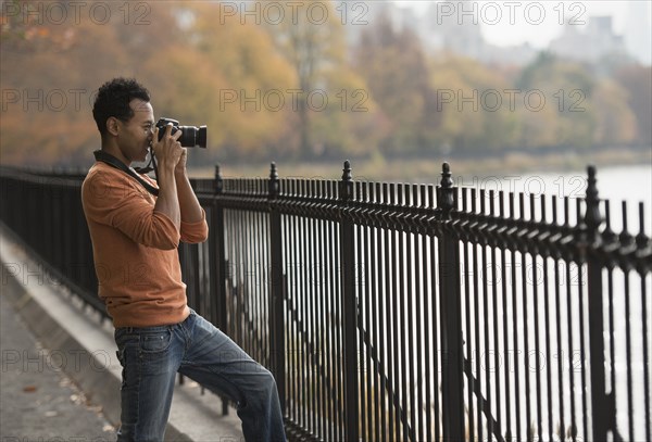 Mixed race man taking photograph on waterfront