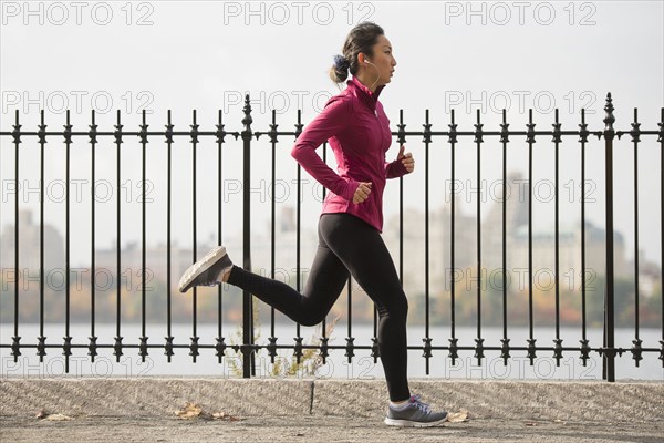 Asian woman running on waterfront path