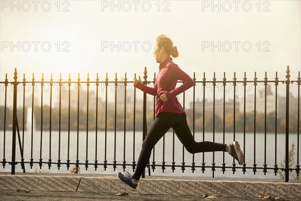 Asian woman running on waterfront path