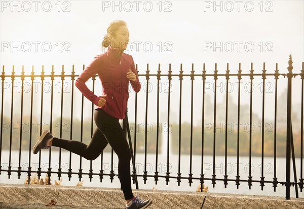 Asian woman running on waterfront path