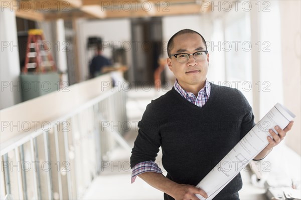 Korean architect carrying blueprints