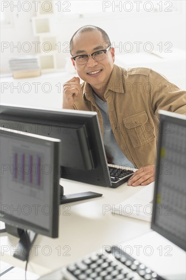 Korean businessman smiling at computer at office desk