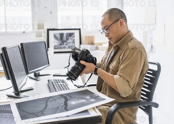 Korean photographer using camera at desk