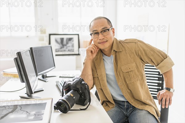 Korean photographer smiling at desk