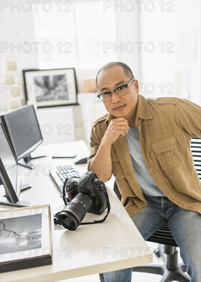 Korean photographer smiling at desk