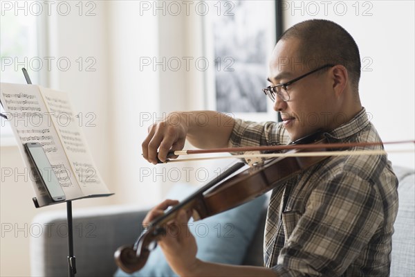 Korean musician playing violin in living room