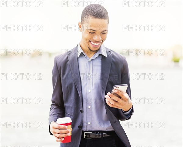 Black businessman using cell phone outdoors