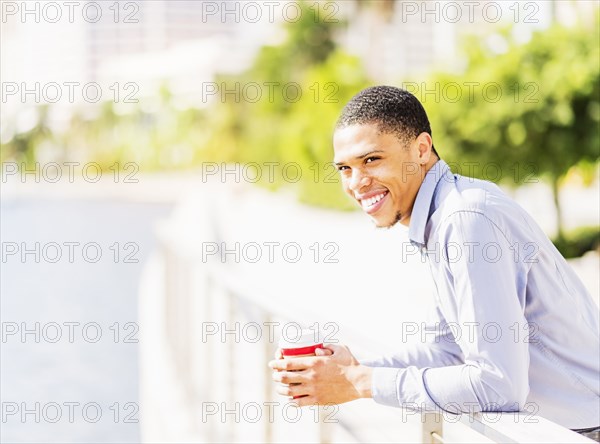 Black businessman leaning on banister at waterfront