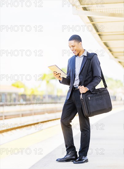 Black businessman using digital tablet on train platform
