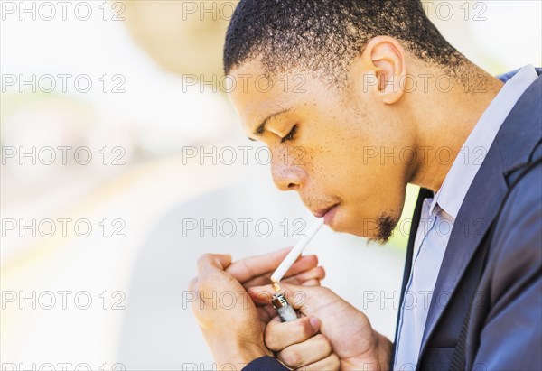 Black businessman lighting cigarette outdoors