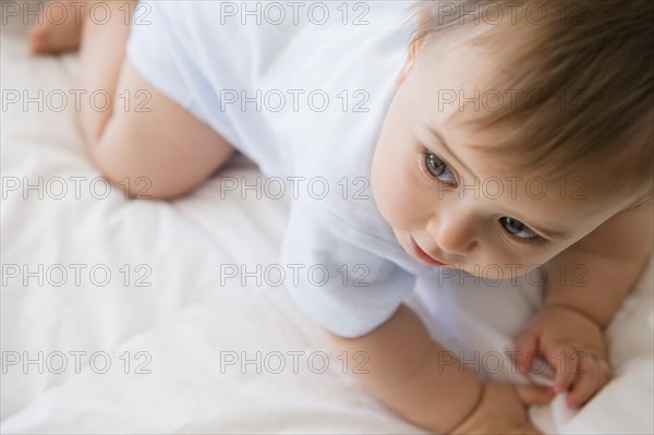 Close up of mixed race baby crawling on bed