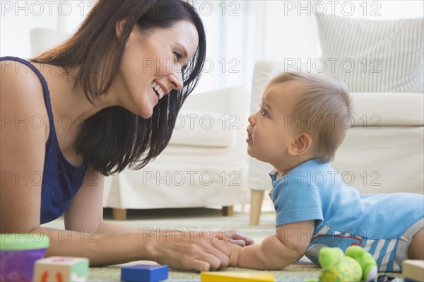 Mixed race mother playing with baby on floor