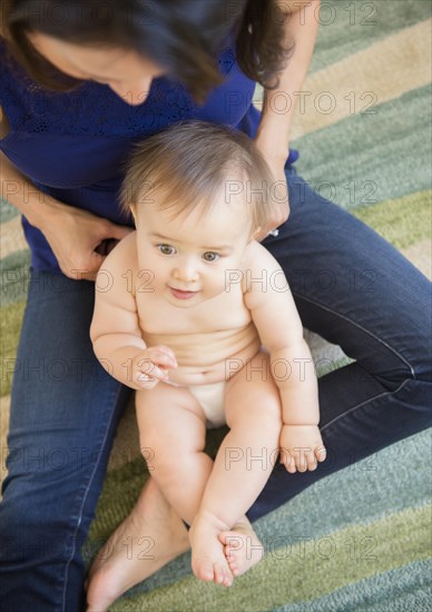 High angle view of mixed race mother playing with baby on floor