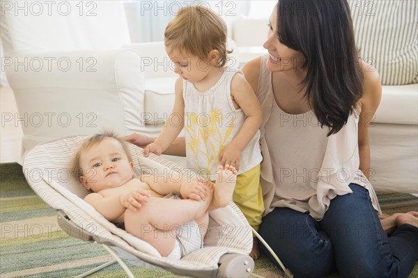 Mother and daughter admiring baby on living room floor