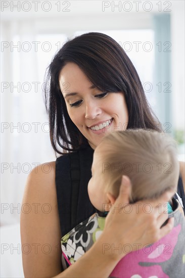 Mixed race mother holding baby in baby carrier