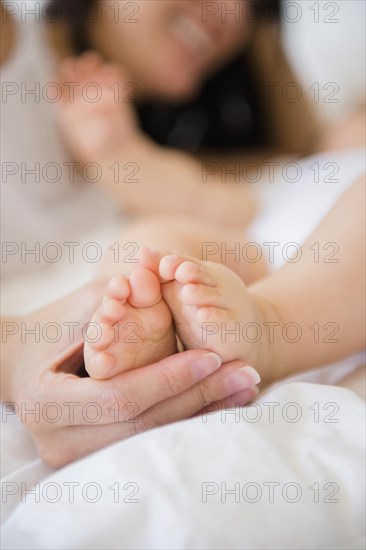 Close up of mixed race mother holding feet of baby