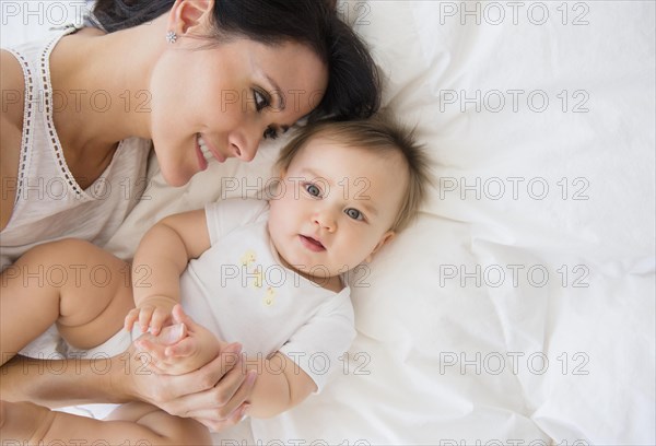 Overhead view of mixed race mother laying with baby on bed