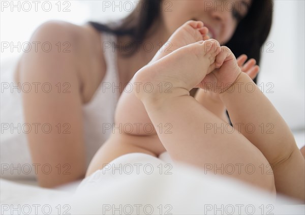 Close up of mixed race mother playing with baby on bed