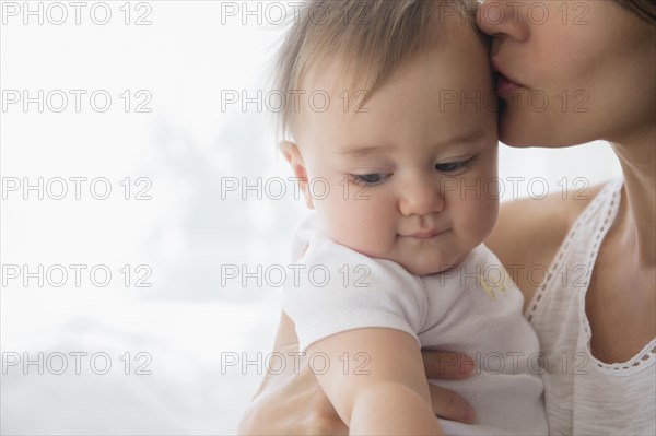 Close up of mixed race mother kissing baby on forehead