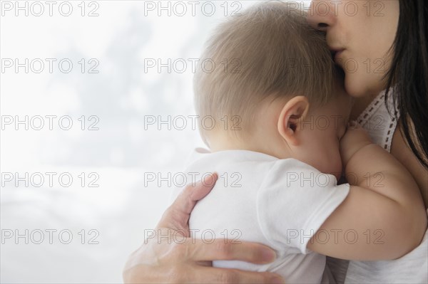 Close up of mixed race mother kissing baby on forehead