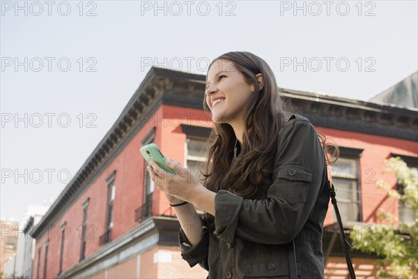 Low angle view of Caucasian woman using cell phone outdoors