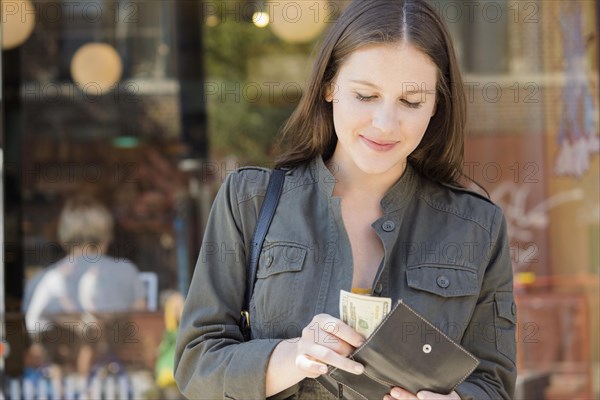 Caucasian woman counting money in wallet