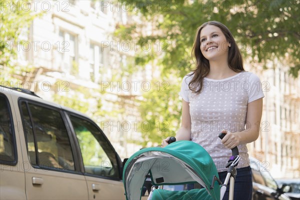 Caucasian mother pushing stroller on urban sidewalk