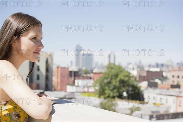 Caucasian woman overlooking cityscape from urban rooftop