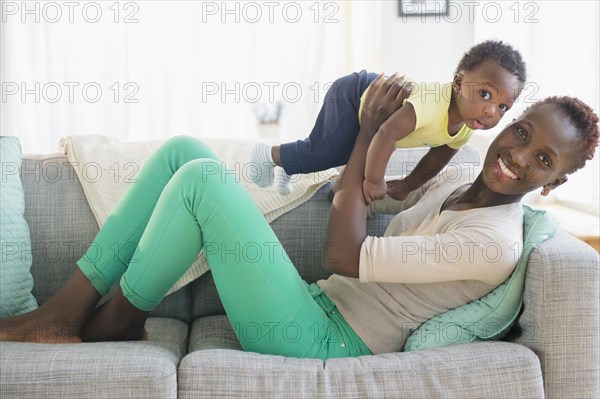 Black mother and son playing on sofa