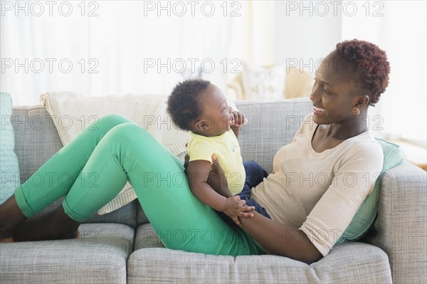 Black mother and son playing on sofa